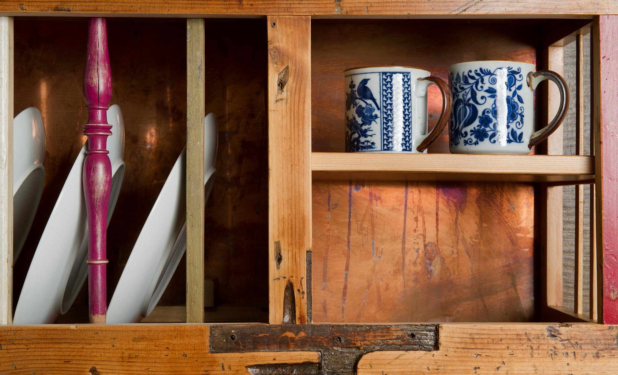 Primo piano del legno utilizzato per creare una piattaia in legno vintage per un casale in Toscana. Nela piattaia sono presenti ceramiche inglesi, tazze e piatti in porcellana antichi